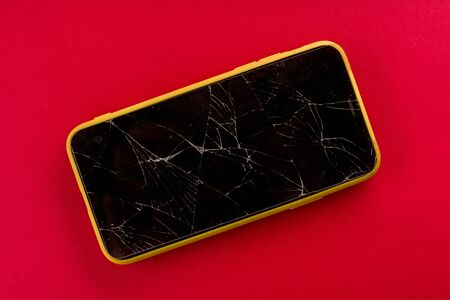 Smartphone with broken screen on red background - imageの写真素材