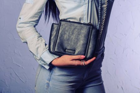 Stylish woman in jeans with small black handbag clutch. fashion concept.の写真素材