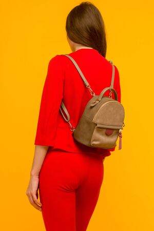 Young girl in a red suit with a small backpack on a yellow backgroundの写真素材