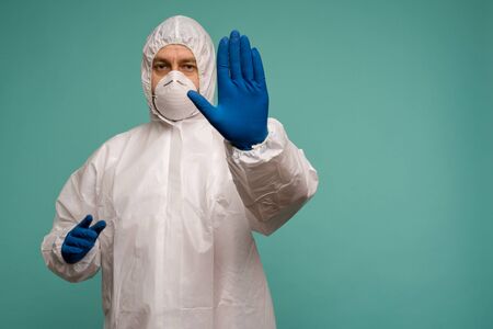 A male doctor in protective overalls and a mask shows stop sign. Coronovirus protection concept in China. - imageの写真素材