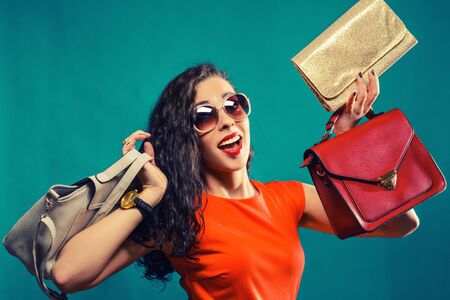 Fashion woman portrait isolated.  Happy girl hold  bags. Red dress. female beautiful model.の写真素材