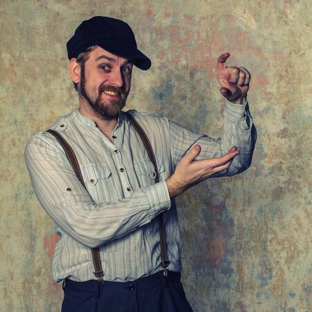 Portrait of handsome young man in white shirt and bow tie adjusting his suspenders and smiling at...