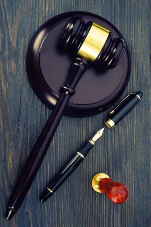 Judge's gavel, fountain pen and a stamp on an old wooden table - Imageの写真素材