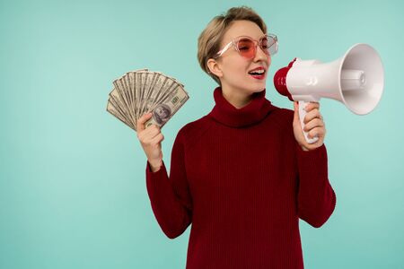 Young woman in pink sunglasses with money yelling to loudspeaker - imageの写真素材