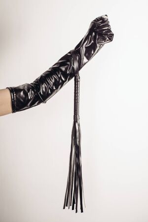 Leather whip in female hand isolated on a white background - imageの写真素材