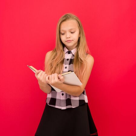 Lovely little girl standing and reading book over red background - imageの写真素材