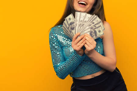 Joyful girl won the lottery and holds a fan of US dollars in her hands on a yellow background - imageの写真素材