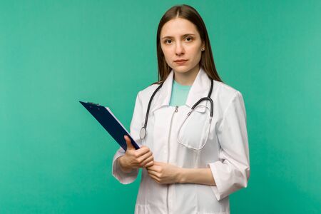 Happy smiling young female doctor with clipboard, isolated over background - imageの写真素材