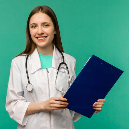 Happy smiling young female doctor with clipboard, isolated over background - imageの写真素材