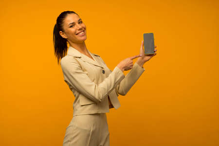 Photo of pleased happy young woman posing isolated over yellow wall background holding money and...