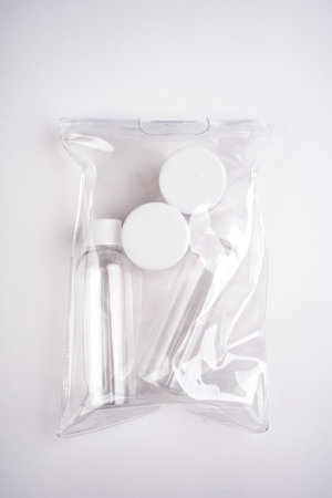 Plastic containers. Travel set on a white background. Plastic bottles for cream, shampoo in a sealed bag. Top view.の写真素材