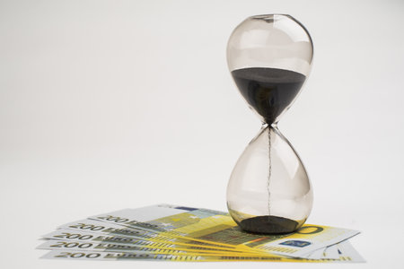 Concept or conceptual euro paper money banknote with a sand glass or time background, metaphor to...