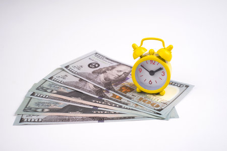 Retro styled alarm clock dollar cash isolated on white. Time is money conceptの写真素材