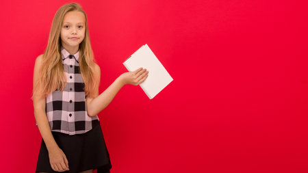 Lovely little girl wearing summer clothes standing isolated over red background, holding a book - imageの写真素材