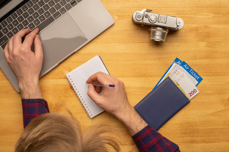 Top view of man working at desk making travel or vacation plan