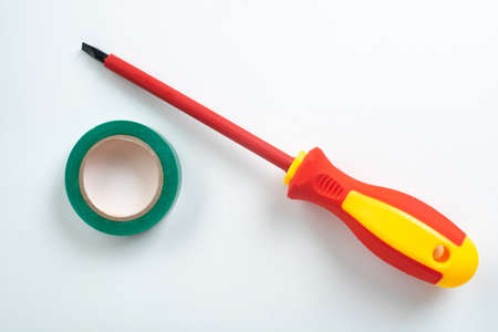Red plastic dielectric screwdriver for electrical work with insulated tip and green insulating tapeの写真素材