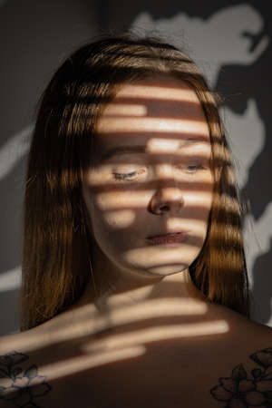 studio portrait of young sad beautiful woman using gobo masksの写真素材