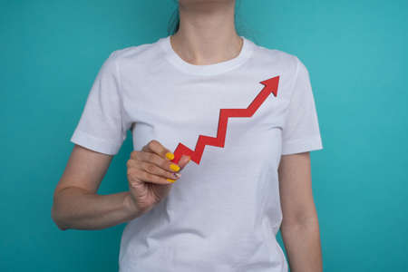 Graph chart growing up in the hand. Success is in your hands. Red arrow up in a woman's hand on a blue background. Price increaseの写真素材