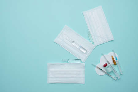 Syringe, mask, ampoules on a blue background, vaccination concept.