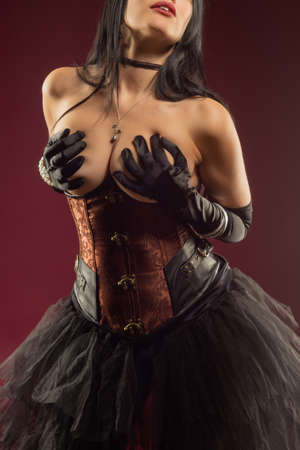 sexy woman posing topless corset burlesque covering her breasts with her handsの写真素材