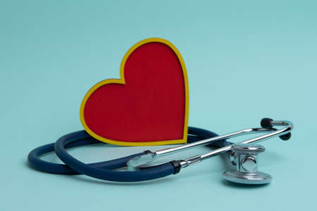 A stethoscope and a red heart on a blue background. The concept of cardiology.の写真素材