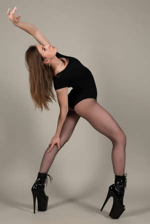 Beautiful flexible girl pole dancer in high heels posing in studioの写真素材