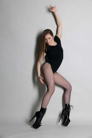 Beautiful flexible girl pole dancer in high heels posing in studioの写真素材