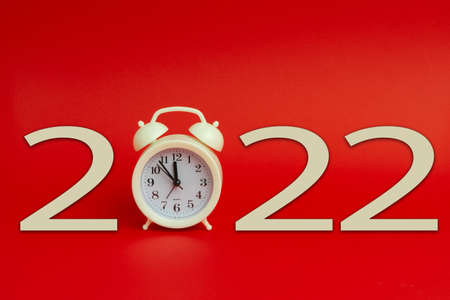 Celebrating new year. New 2022 year made with alarm clock on red background.の写真素材