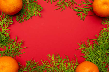 Christmas or New Year red background, framed by a Christmas tree, tangerines, seasonal decorations,...