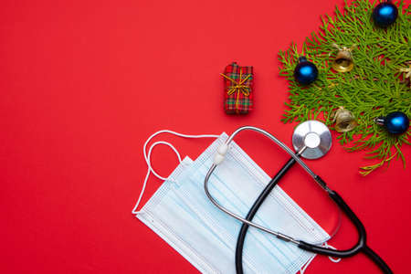 Long wide Christmas banner with festive decorations, medical stethoscope and facial masks on red background. Christmas greeting card for medics concept.の写真素材