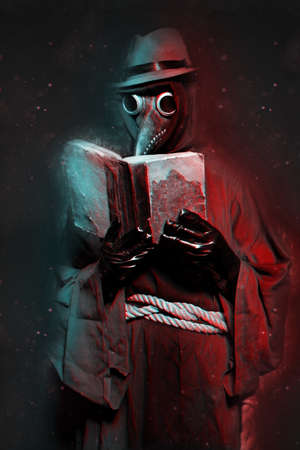 A man dressed as a plague doctor is reading an old book. halloween holidayの写真素材