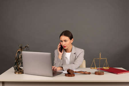 Lawyer office. Statue of Justice with scales and lawyer working on a laptop. Legal law, advice and justice conceptの写真素材