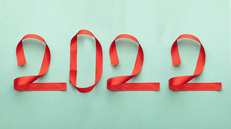 Numbers 2022 from red ribbons on a blue background. New Year Christmas