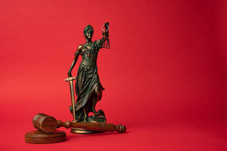 gavel and the statue of justice on a red backgroundの写真素材
