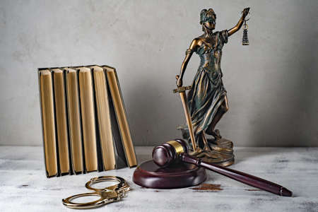Lady Justice, Judge's gavel, books, handcuffs on an old wooden table