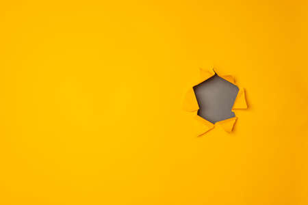 Big paper torn hole in yellow background with copy space.の写真素材