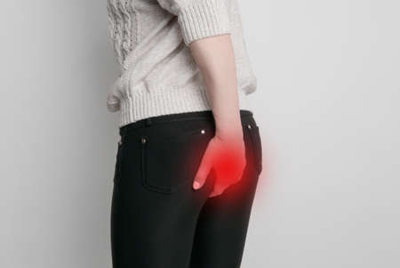 Woman hand holding her bottom because having Abdominal pain and Hemorrhoids, Health care concept.