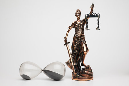 Justilia or Themis (Symbol of Justice) statue and hourglass isolated on white background with clipping pathの写真素材
