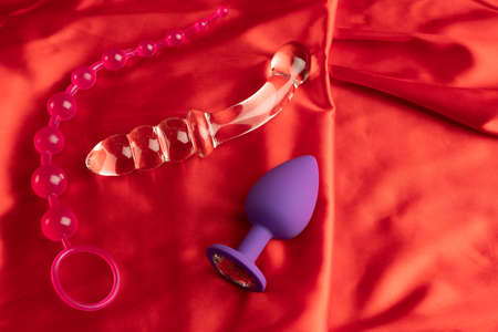 a collection of different types of sextoys on red satinの写真素材