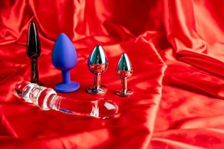 a collection of different types of sextoys on red satinの写真素材