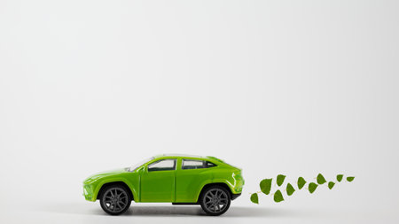 A toy green car rides over the background with an exhaust from birch leaves. The concept of reducing CO2 emissions from vehicles.の写真素材