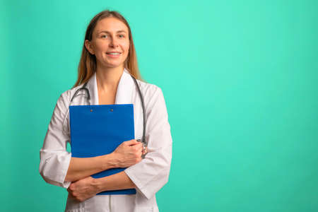 Young attractive woman nurse or doctor in a white coat with file on background.の写真素材