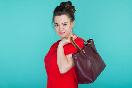 Beautiful woman in red dress posing sits on chair against the wall in rococo styleの写真素材