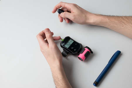 A man with diabetes is tested with a glucometer to find out his blood sugar level.の写真素材