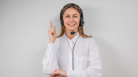 Portrait of smiling support female phone operator in headset, against gray background. Consulting...