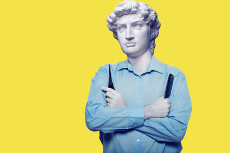 Abstract modern collage. The man with the plaster head of David in a red sweater looks at a laptop screen where does the hand with the credit card come out on a yellow backgroundの写真素材