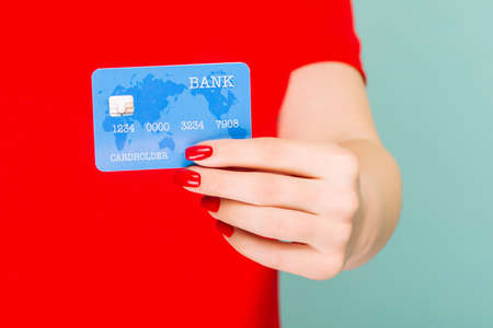 Woman hand with credit card isolated on blue background.の写真素材