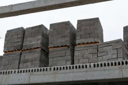 Concrete blocks for construction on wooden pallets are located in an outdoor warehouse, closeup.