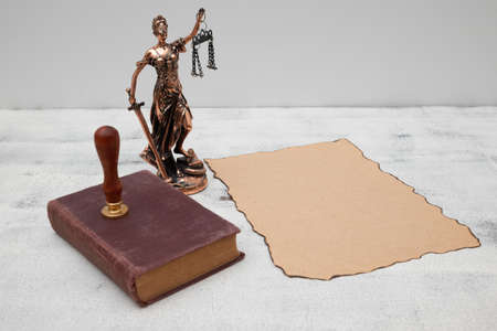 Lady Justice, old book and parchment scroll with seal and stamp on an old wooden table. law and...