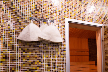 The interior of a small Finnish sauna with wooden walls. On the wall hang hats made of felt for a bath.の写真素材